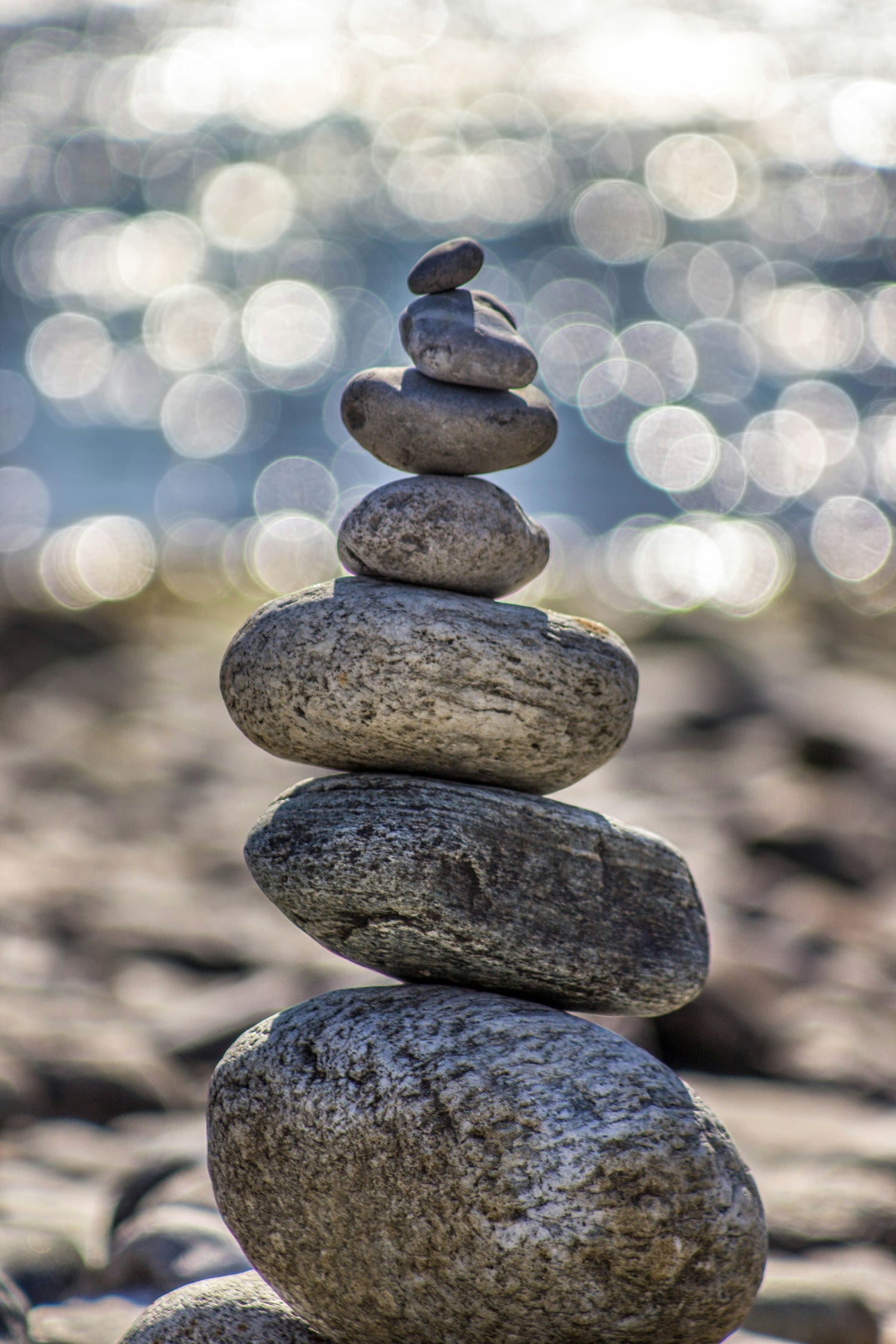 A zen stone stack with out of focus water behind.